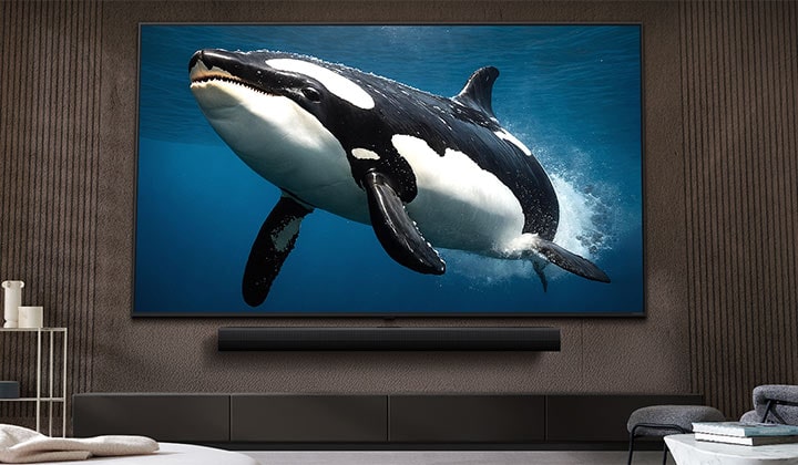 Televisor LG con una pantalla impresionantemente grande montado en una pared sobre una barra de sonido LG en un salón de estilo moderno.	