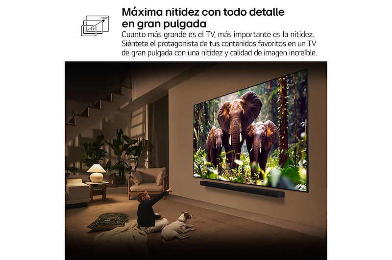 Una niña y un perro están sentados frente a un televisor LG QNED TV montado en una pared con una barra de sonido LG Soundbar. En pantalla muestra a tres elefantes caminando hacia adelante. El título hace referencia a cómo cada acción es más emocionante en una pantalla gigante.