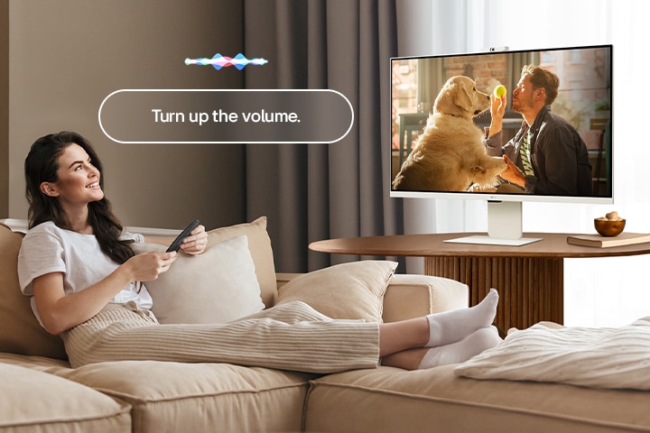 Una mujer está subiendo el volumen al LG Smart Monitor utilizando el Magic Remote.