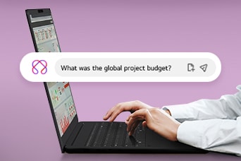 Esta imagen muestra unas manos escribiendo en un portátil, con una barra de búsqueda que muestra la pregunta: "¿Cuál fue el presupuesto global del proyecto?"