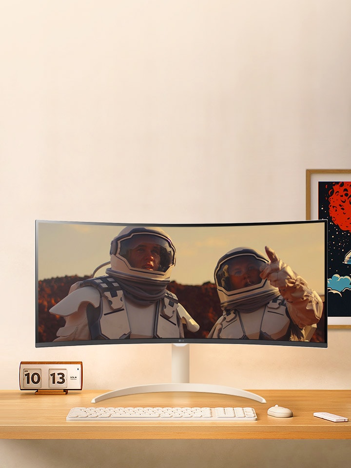 Hay un monitor encima del escritorio con una película reproduciéndose en la pantalla.