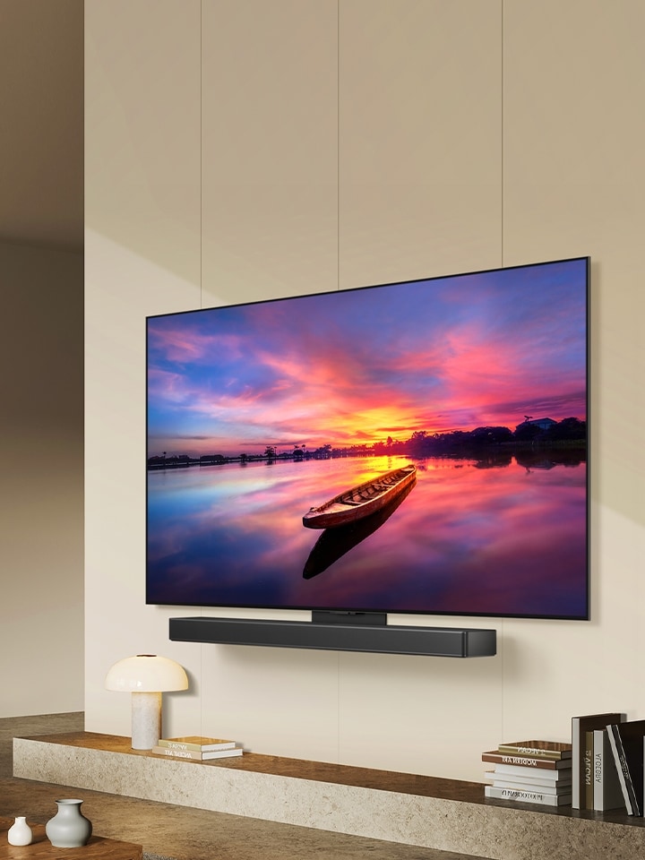 Un TV LG OLED C4 orientée à 45 degrés vers la gauche, affichant un beau coucher de soleil avec un bateau sur un lac. Le téléviseur est équipé d'une barre de son LG SC9S* installée via le support Synergy dans un espace de vie minimaliste.