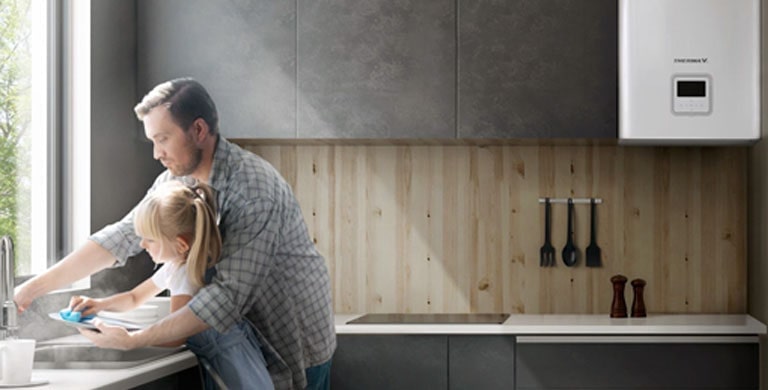 A father and a young daughter are washing dishes together with hot water in the kitchen.