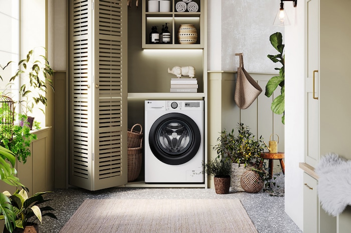 Lave-linge LG F14R15WHS blanc installé dans une buanderie confortable avec des placards à persiennes et des plantes vertes.