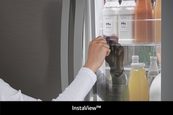 Réfrigérateur InstaView French Door LG GMZ765SBHJ Acier Foncé: une main saisit une bouteille par la fonction Door-in-Door dans le compartiment éclairé.