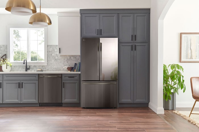 Réfrigérateur InstaView French Door LG GMZ765SBHJ Acier Foncé, intégré élégamment dans une cuisine moderne aux armoires bleu marine et suspensions dorées.