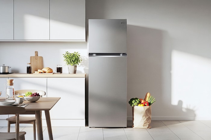 Réfrigérateur Top-Freezer LG GTB332PZGE Argent Premium, intégré avec élégance dans une cuisine moderne et minimaliste avec armoires blanches et accents de bois.