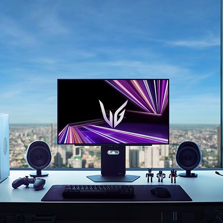 Moniteur LG 27GX790A au centre d'une configuration de jeu premium, présentant une ambiance de pièce sombre avec vue sur la ville et des périphériques optimisés pour un jeu immersif.