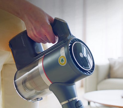 La main d'une femme qui tient la poignée de l'aspirateur.