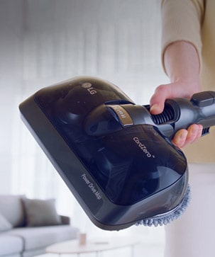 The head of the vacuum is shown reaching beneath a piece of furniture to clean the difficult to reach hard floor easily.
