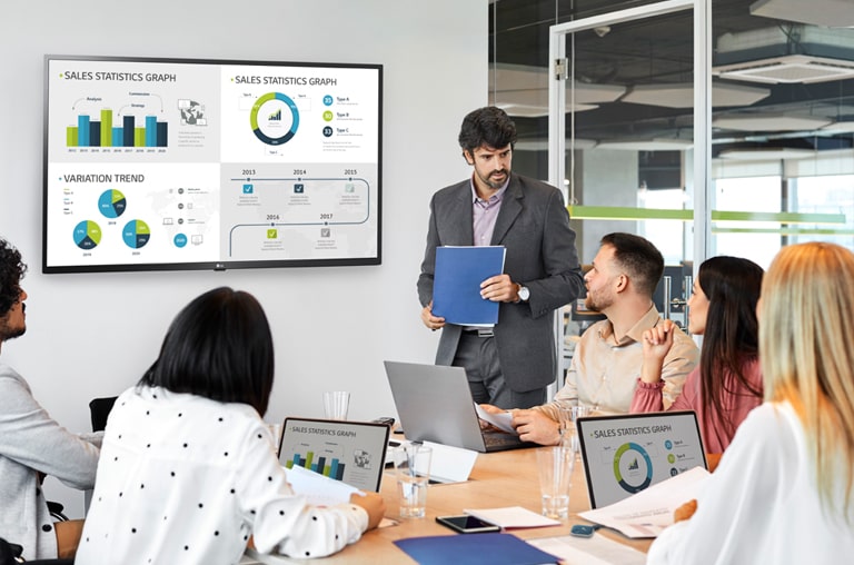 6 personnes participent à une réunion et 4 écrans d’ordinateur sont simultanément partagés sur un grand affichage accroché au mur, grâce au dongle USB connecté aux ordinateurs.