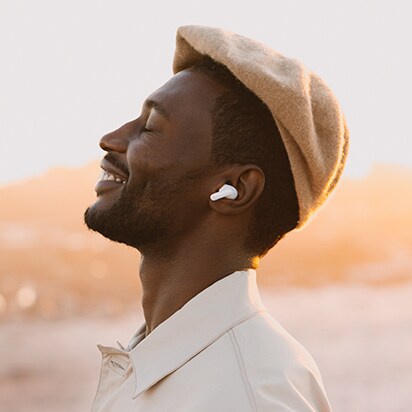 Vue de profile d'un homme souriant avec les yeux fermés portant des TONE Free blancs