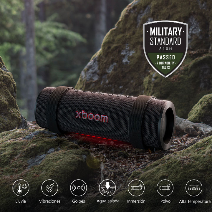 La xboom Grab est placée sur une pierre recouverte de mousse. Sur le côté droit ci-dessus, on voit le logo standard militaire.