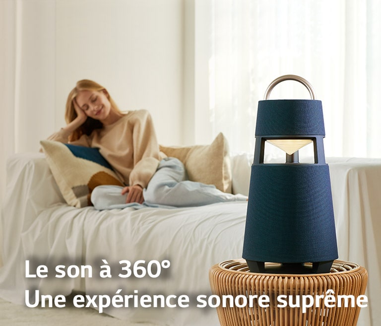 Image d’une femme assise sur un canapé écoutant de la musique grâce à une enceinte XBOOM 360 posée devant elle.