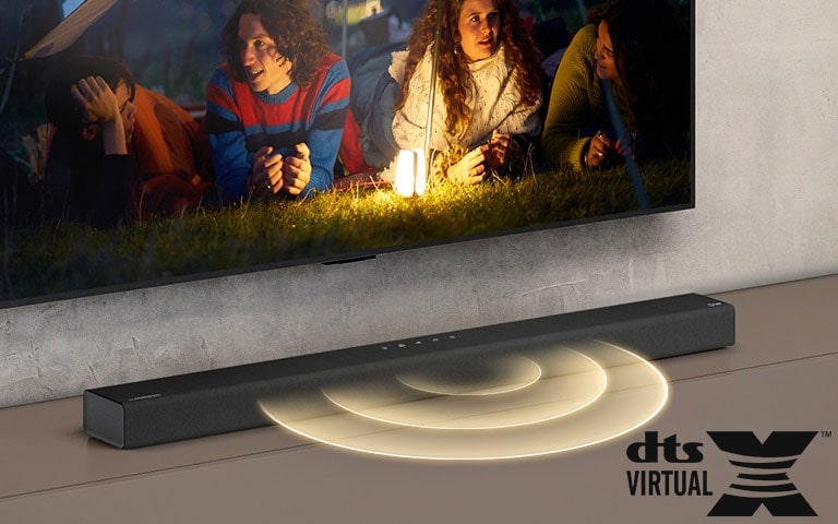 Le téléviseur LG est accroché au mur ; l’écran montre 2 couples allongés sur l’herbe. Devant eux se trouve une lampe. La barre de son LG se trouve sous le téléviseur LG. Un graphique représentant du son sort de l’avant de la barre de son. Le logo DTS Virtual:X est visible dans le coin inférieur droit de l’image.
