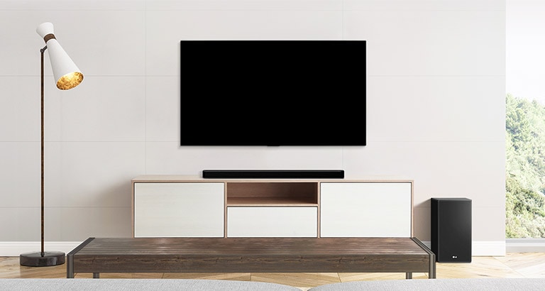 Un téléviseur, une barre de son et un caisson de basses installés dans un salon simple.