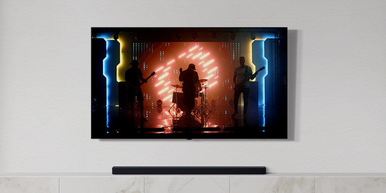 On peut voir un téléviseur et une barre de son dans un salon blanc. Groupe de musiciens jouant des instruments et chantant une chanson sur un écran de télévision. (Reproduire la vidéo)