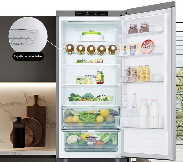 Réfrigérateur rempli d'aliments frais avec porte ouverte présentant un porte-bouteilles et une clayette rétractable.