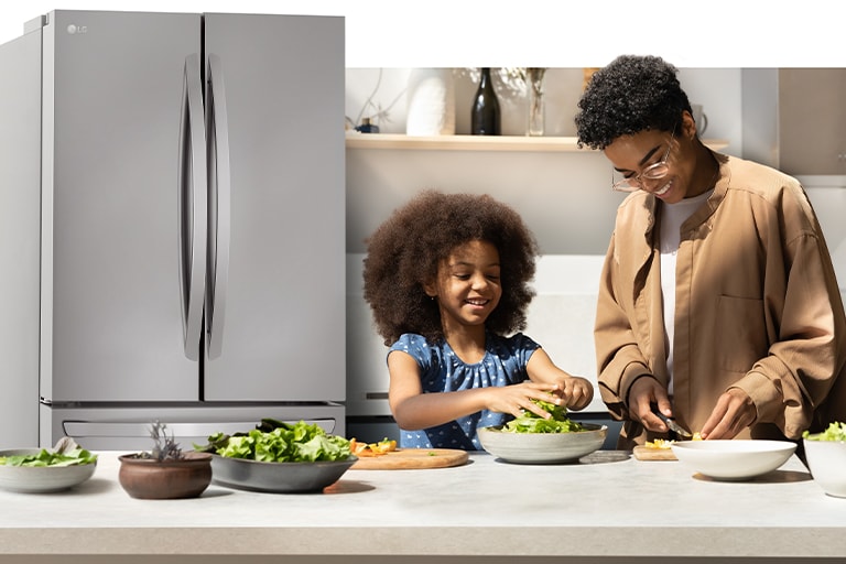 Un adulte et un enfant préparent à manger dans la cuisine, avec un réfrigérateur éclairé