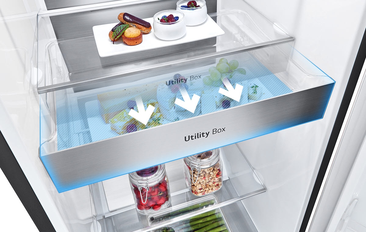 L'intérieur du réfrigérateur montre le tiroir étiqueté ''Utility Box''. Trois flèches poussent vers l'extérieur, indiquant que le tiroir peut être retiré pour accéder aux aliments qu'il contient.