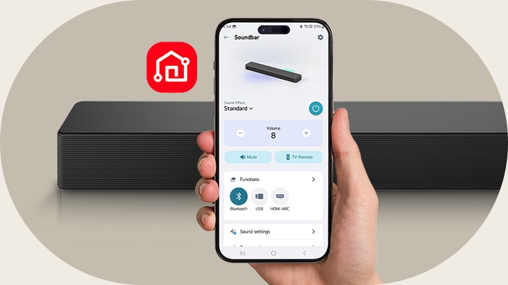 Un smartphone affichant l’écran de l’application LG ThinQ est tenu en main. À côté, l’icône de l’application LG ThinQ est visible. La barre de son SH5A est placée en arrière-plan.
