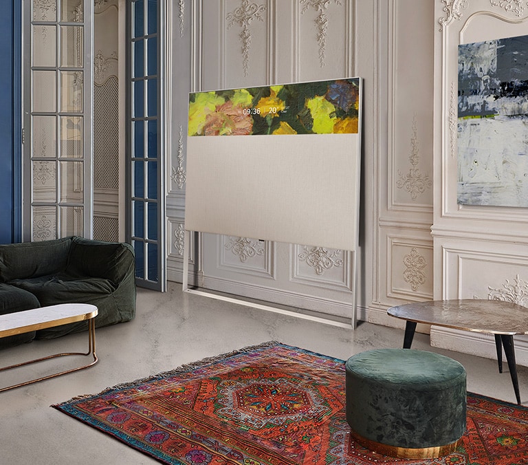 EASEL en mode affichage en ligne appuyé contre un mur avec moulure décorative. Il se trouve à côté d’une peinture sur le mur et derrière un tapis aux motifs complexes.