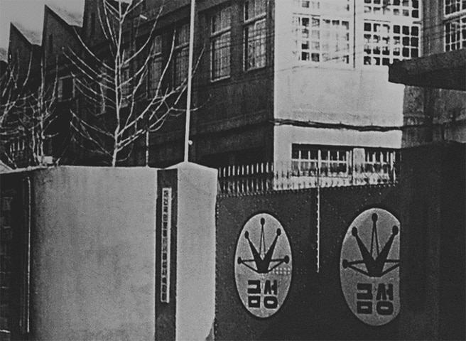 Black-and-white photo of the original GoldStar factory entrance, with the old company logo displayed on the gate