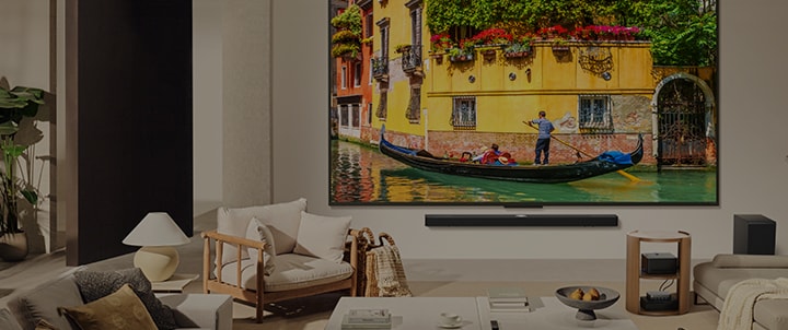 QNED M mounted on a cozy living room wall, with the ZeroConnect box visible on the side table.