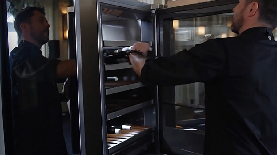 one chef is taking a bottle of wine from the lg signature wine cellar refrigerator at the lg signature and evian championship event