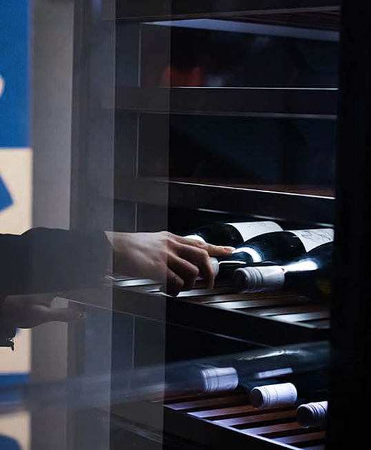 one woman is opening and taking a bottle of wine from lg signature wine cellar at the lg signature artweek in germany