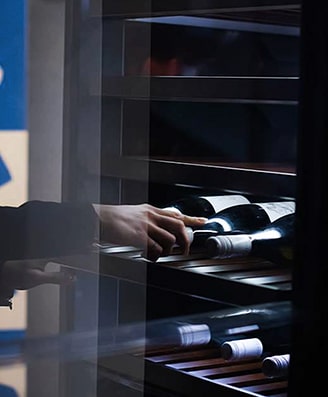 one woman is opening and taking a bottle of wine from lg signature wine cellar at the lg signature artweek in germany