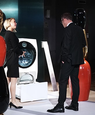 several people are talking in front of lg signature washing machine at artweek in germany