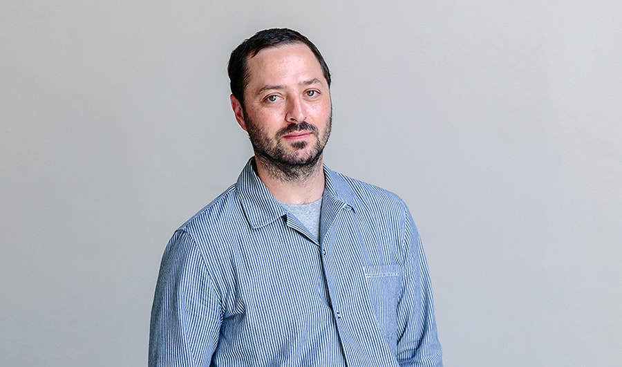 front image of creator alexis christodoulou who is putting his both hands in his pockets wearing blue shirt