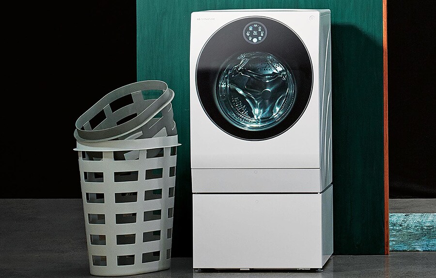close shot of lg signature washing machine with a laundry basket in the green tone laundry room