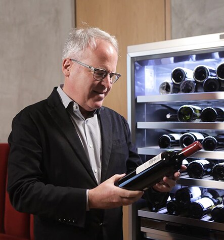 James Suckling is looking at a wine in front of LG SIGNATURE Wine Cellar.