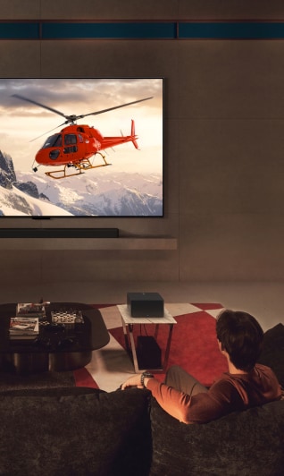 In a luxurious living room with a view of the night skyline, a performance of a male ballet dancer and a female ballerina is playing on the OLED M TV mounted on the wall.