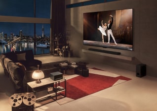 In the evening-lit living room, a man is sitting on the sofa with his dog, watching a scenic movie. On the table in front of them, there is a zero connect box placed.