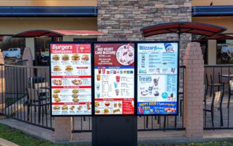 A photo of a digital sinage with a burger menu and drink menu