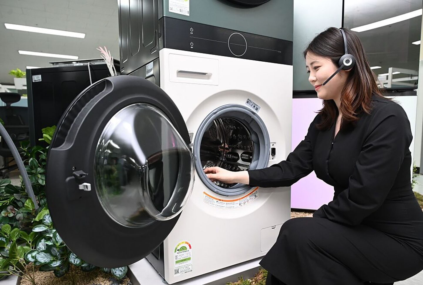 A woman with headphones on sitting next to a washer