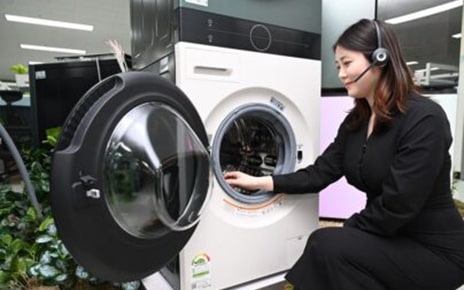 A woman with headphones on sitting next to a washer