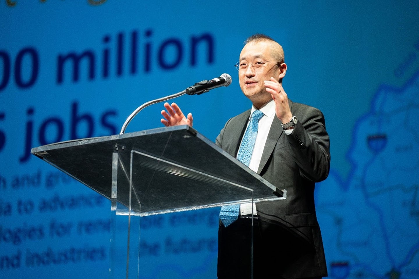 A photo of Sokwoo Rhee on stage speaking