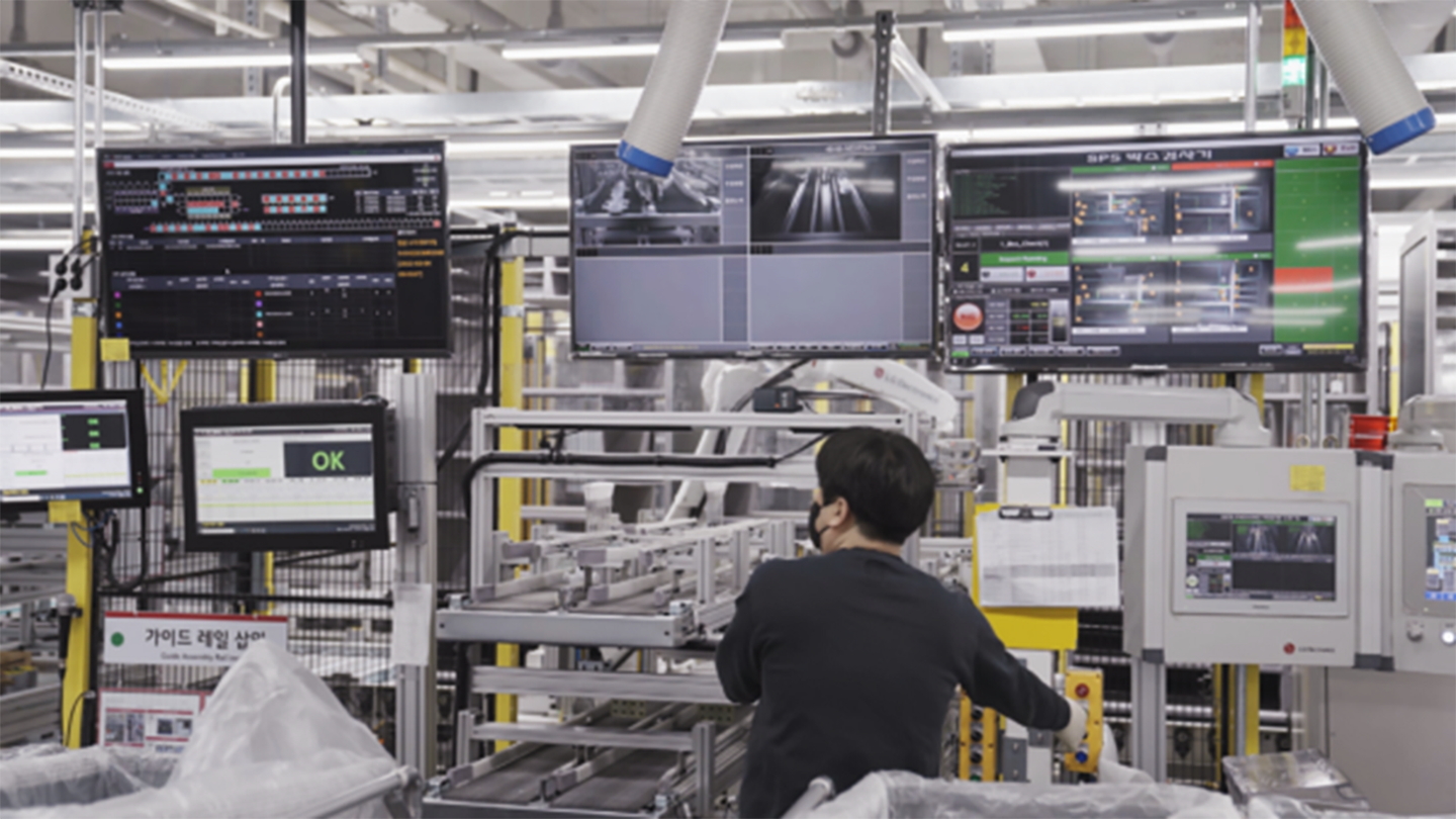 A photo of a factory worker working while looking up the screen
