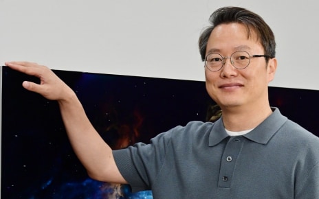 LG expert standing beside an LG OLED evo TV featuring Reflection Free Premium for bright-room viewing.
