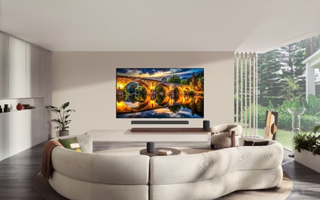 A wall-mounted LG TV displays an illuminated stone bridge reflected in calm water in a modern living room.