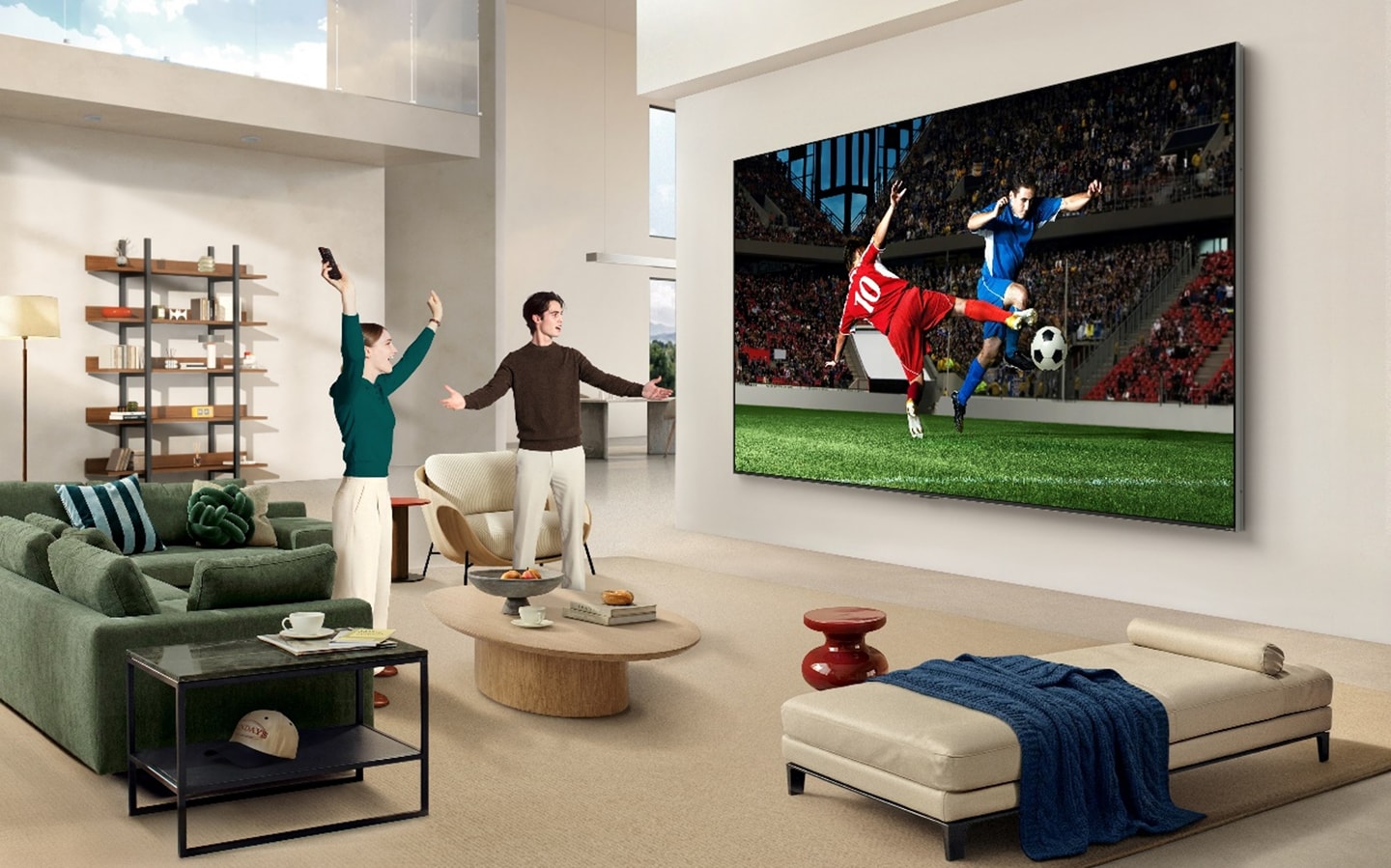 Two people cheer while watching a soccer match on an ultra-large LG QNED evo AI Mini LED TV in a modern living room.