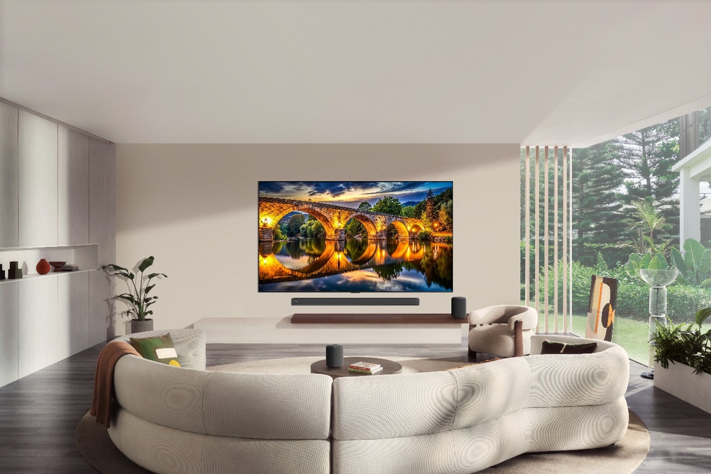 A wall-mounted LG TV displays an illuminated stone bridge reflected in calm water in a modern living room.