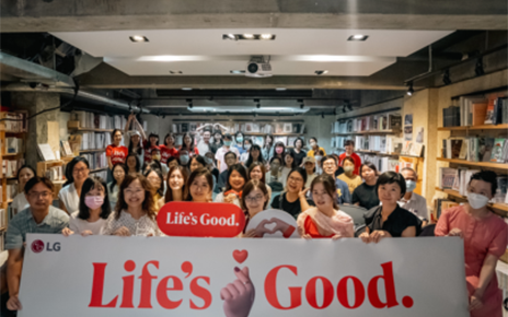 A picture of a group of people at the forum holding up the Life's Good banner