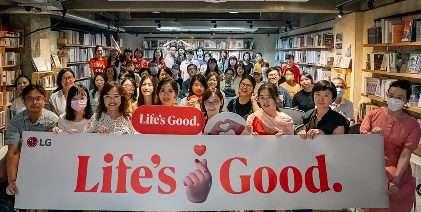 A picture of a group of people at the forum holding up the Life's Good banner
