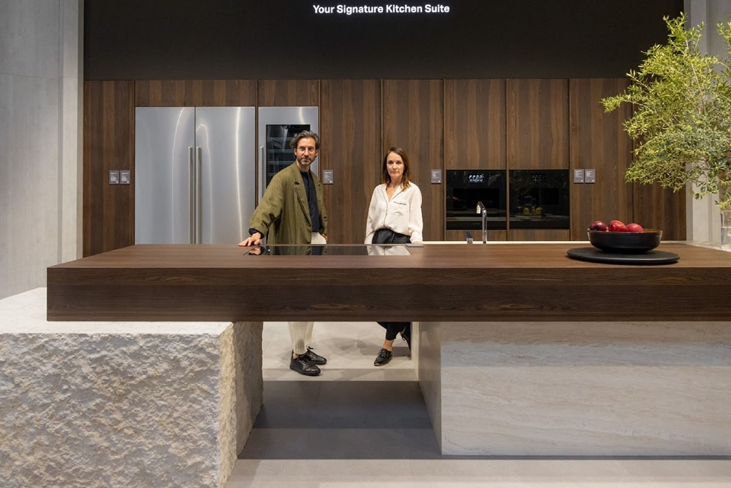 A man and a woman standing at the signature kitchen suite display area