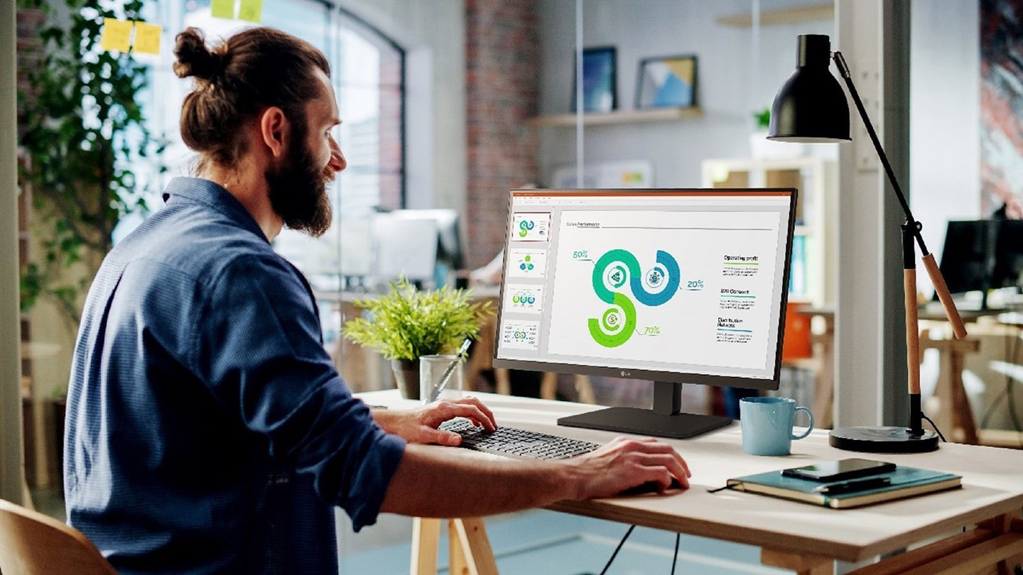 A picture of man sitting down on the desk, using LG Full HD Monitor (model 27BA560)